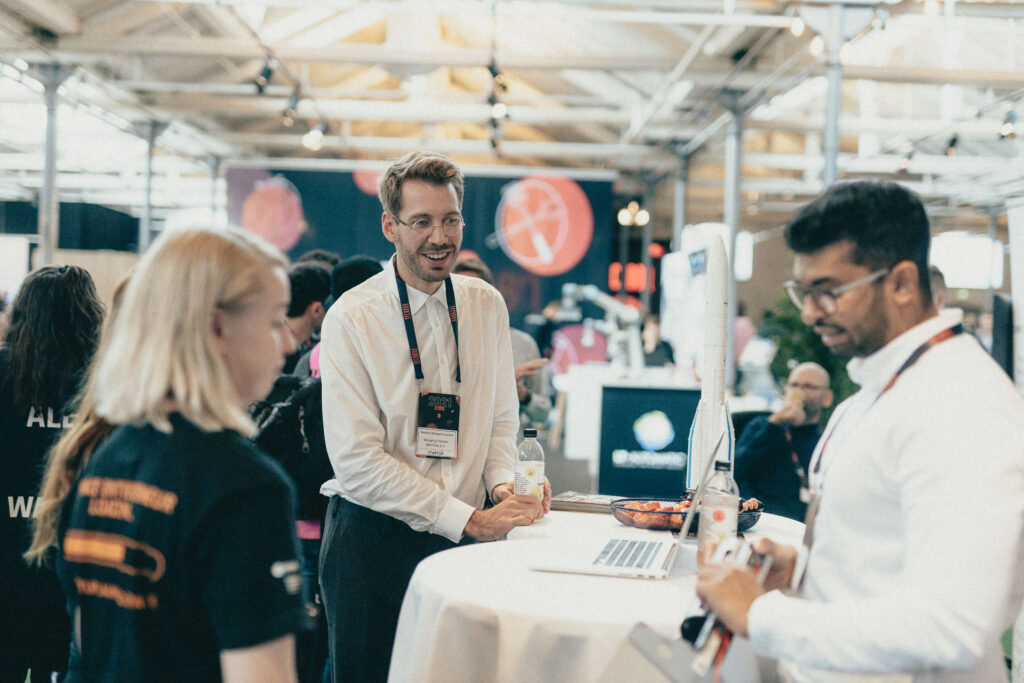 Smiling people gathered around a startup booth at the TechBBQ 2022 summit