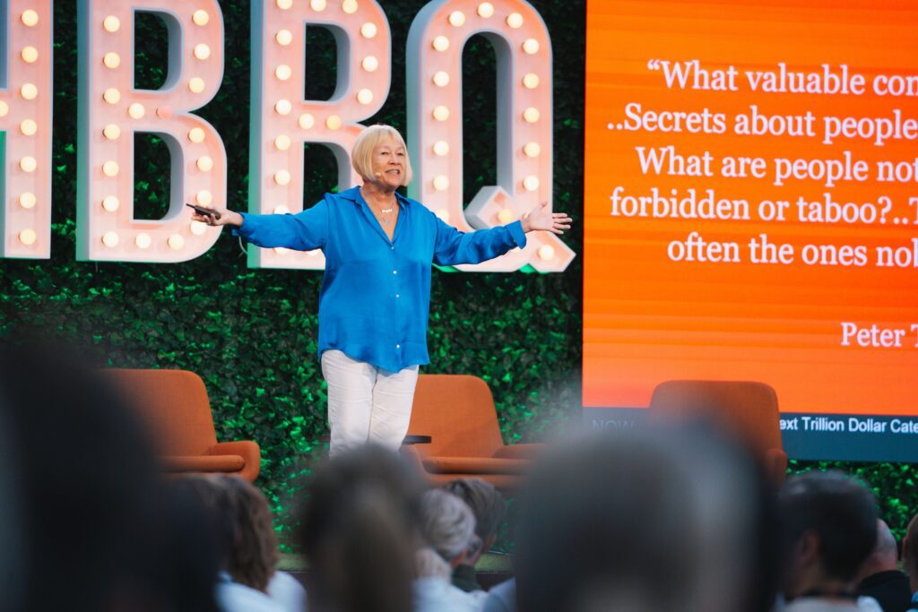 Speaker with arms wide open at a conference stage.