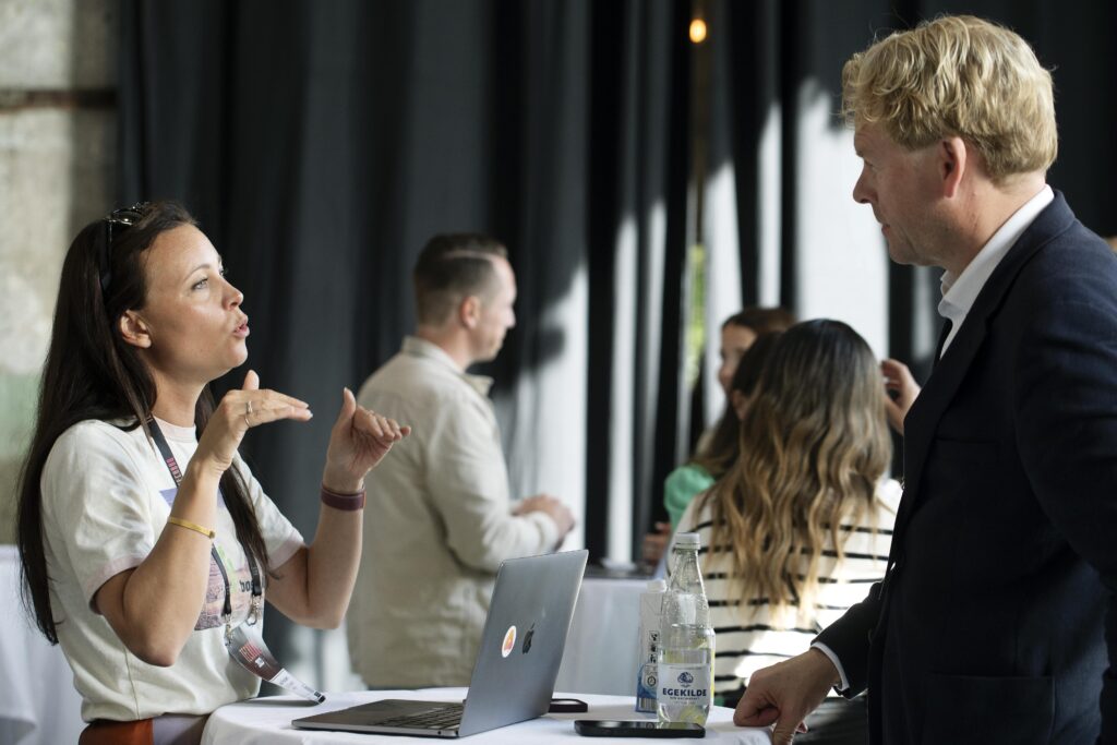 Woman engaged in conversation with a man at TechBBQ, with a laptop on the table.