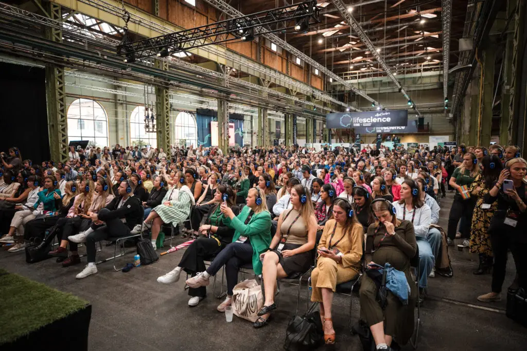 Large seated audience wearing headphones at TechBBQ.