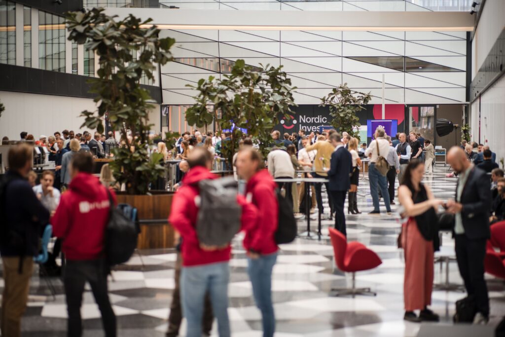 A vibrant networking area at TechBBQ, with attendees mingling near "Nordic Invest" banners.